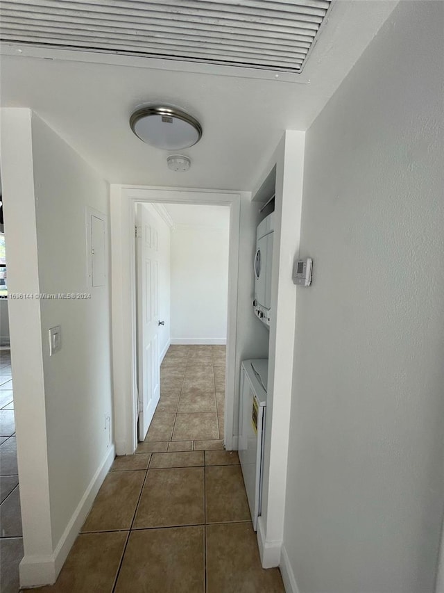 corridor featuring dark tile patterned flooring and stacked washer and clothes dryer