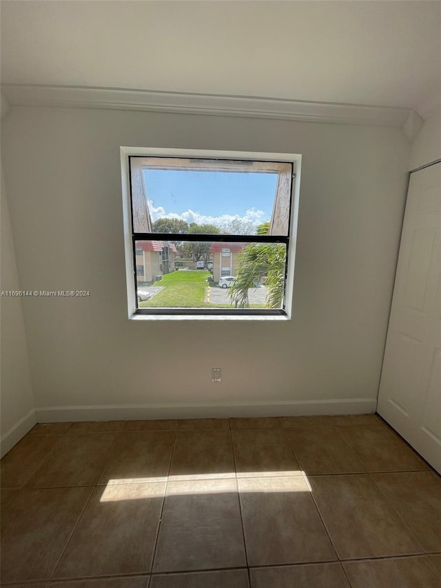 spare room with dark tile patterned floors and ornamental molding