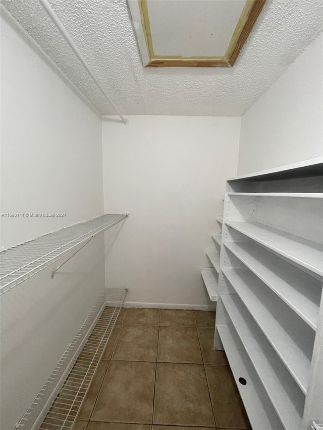 spacious closet featuring dark tile patterned flooring