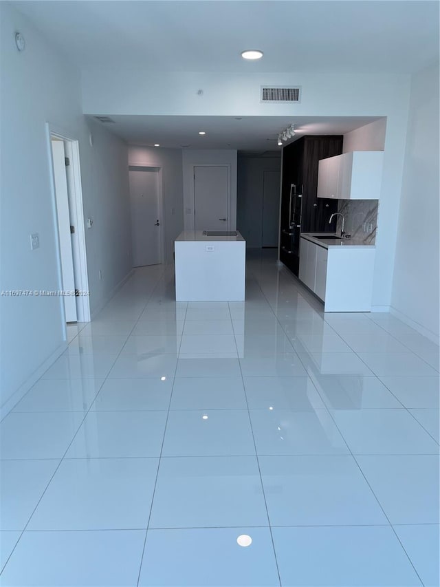 kitchen with decorative backsplash, white cabinetry, sink, and light tile patterned floors