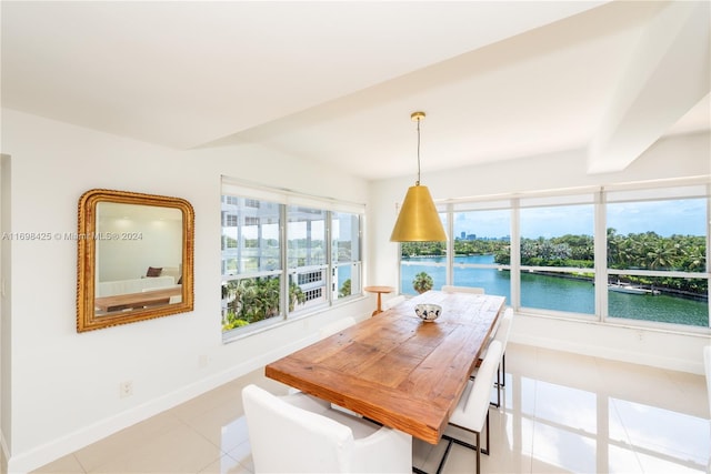 dining space with beamed ceiling, light tile patterned flooring, and a water view