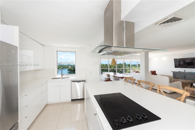 kitchen with sink, light tile patterned floors, appliances with stainless steel finishes, island range hood, and white cabinetry