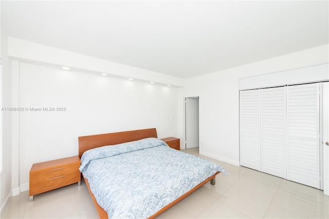 bedroom with light tile patterned floors, baseboards, and a closet