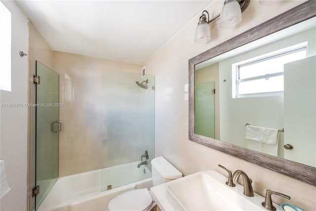 full bathroom with sink, combined bath / shower with glass door, and toilet