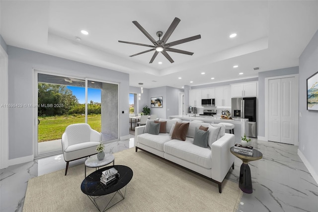 living room featuring ceiling fan and a tray ceiling