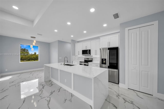 kitchen with white cabinetry, a center island with sink, appliances with stainless steel finishes, light stone counters, and sink