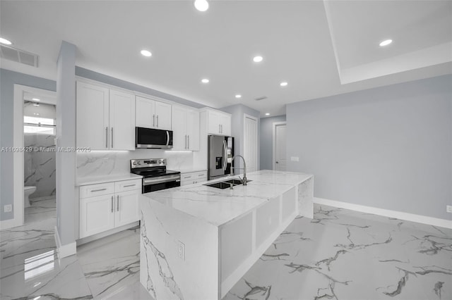 kitchen with white cabinetry, stainless steel appliances, and an island with sink