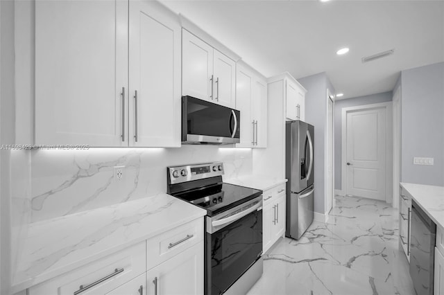 kitchen featuring appliances with stainless steel finishes, decorative backsplash, white cabinetry, and light stone counters