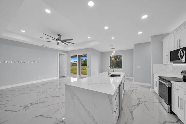 kitchen featuring white cabinets, a kitchen island with sink, light stone countertops, and stainless steel appliances