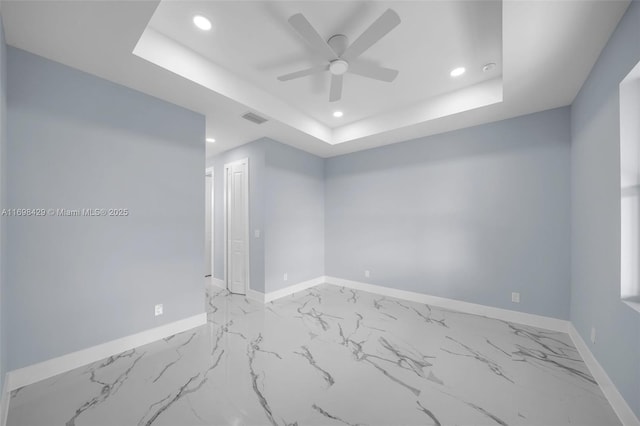 unfurnished room featuring ceiling fan and a tray ceiling