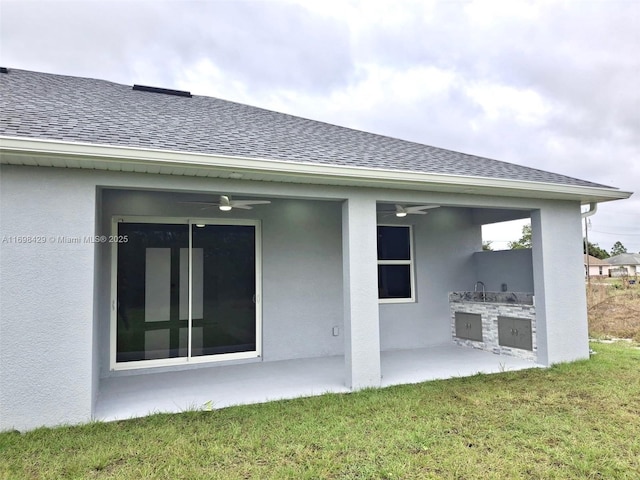 rear view of house featuring ceiling fan, an outdoor kitchen, a yard, and a patio