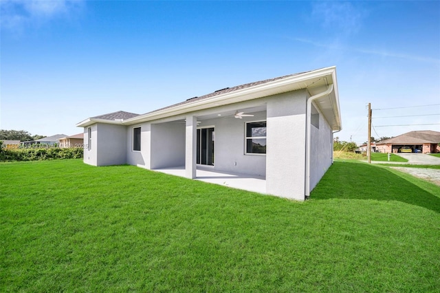 rear view of property featuring a lawn, ceiling fan, and a patio