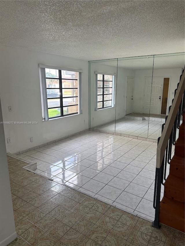 spare room with light tile patterned floors and a textured ceiling