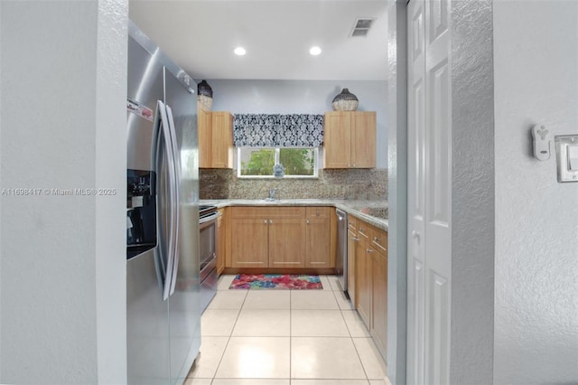 kitchen with backsplash, appliances with stainless steel finishes, and light tile patterned flooring