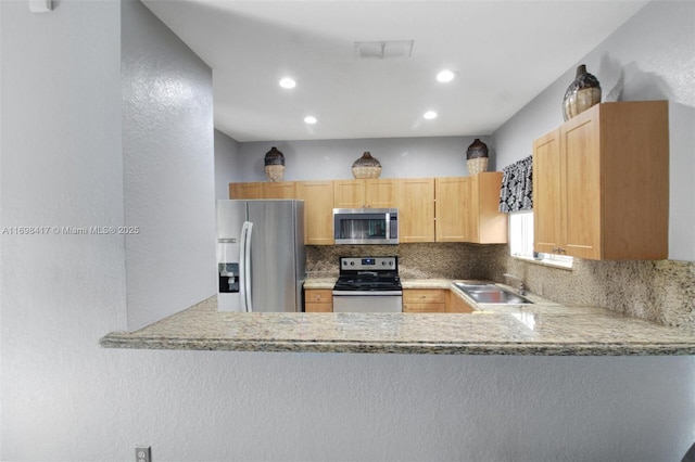 kitchen with light brown cabinetry, light stone countertops, sink, and stainless steel appliances