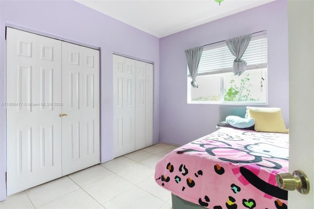 bedroom with light tile patterned floors and multiple closets