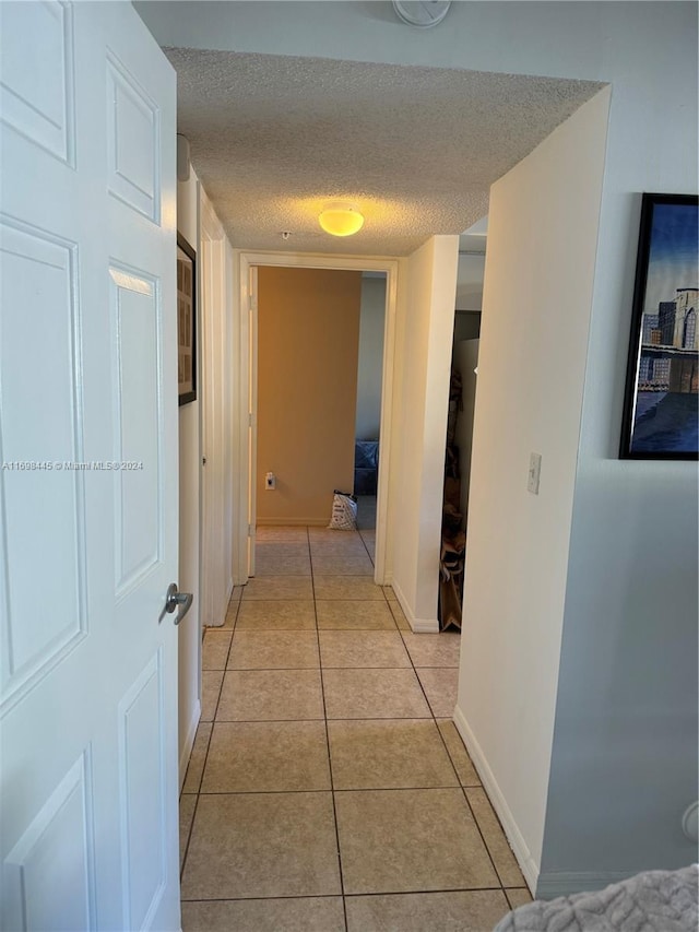 hall featuring a textured ceiling and light tile patterned flooring