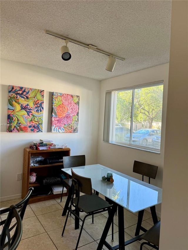 dining area featuring a textured ceiling, breakfast area, light tile patterned floors, and track lighting