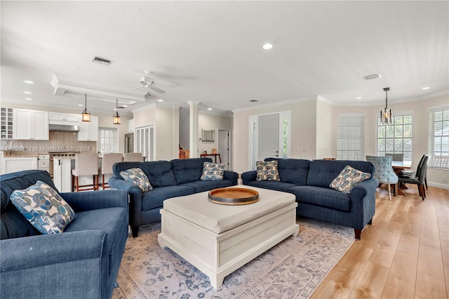 living room with ceiling fan, sink, ornamental molding, and light wood-type flooring