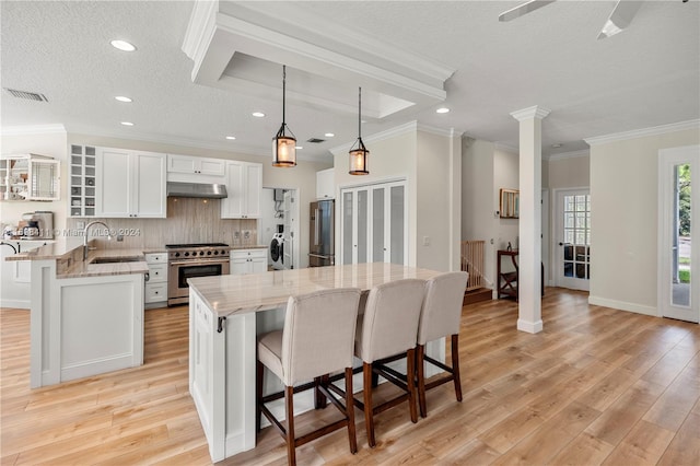 kitchen featuring light stone counters, ventilation hood, high end appliances, white cabinets, and light hardwood / wood-style floors