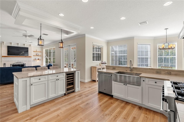 kitchen with sink, beverage cooler, pendant lighting, a center island with sink, and white cabinets