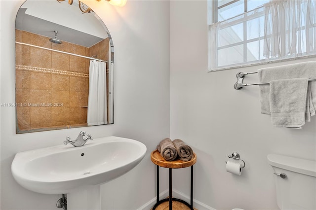 bathroom featuring curtained shower, sink, and toilet