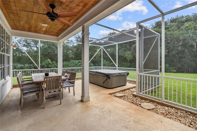 view of patio / terrace featuring glass enclosure, ceiling fan, and a hot tub