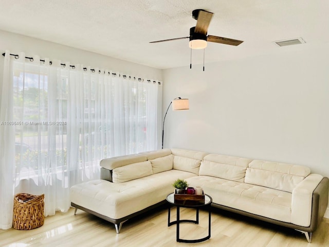 living room with ceiling fan, light hardwood / wood-style floors, and a textured ceiling