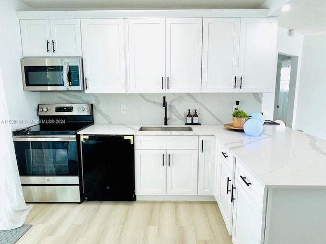 kitchen featuring sink, light hardwood / wood-style floors, light stone counters, white cabinetry, and stainless steel appliances