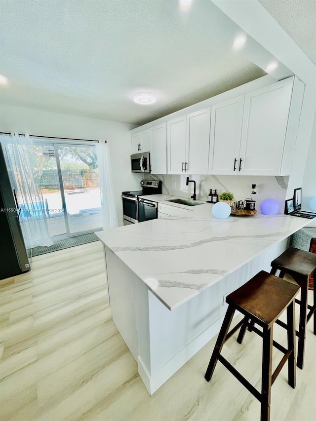 kitchen featuring white cabinets, appliances with stainless steel finishes, a breakfast bar, and sink