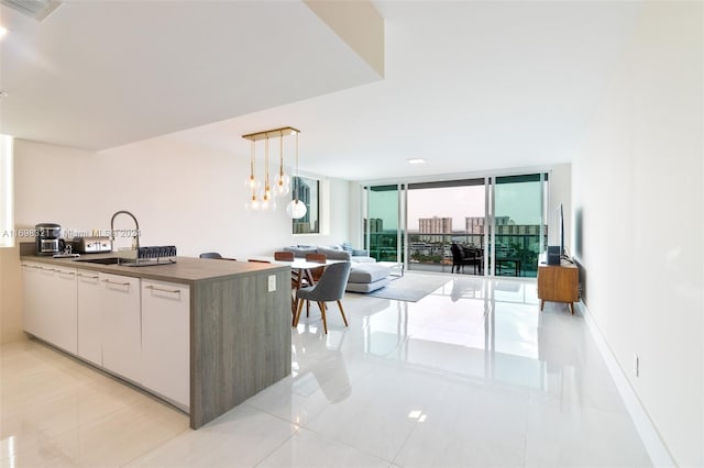 kitchen featuring hanging light fixtures, light tile patterned floors, an inviting chandelier, expansive windows, and white cabinets