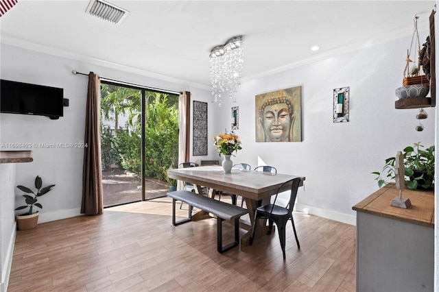 dining room with crown molding, light hardwood / wood-style flooring, and a notable chandelier