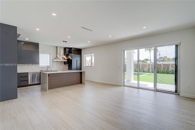 kitchen with pendant lighting, a center island, stainless steel appliances, and wall chimney exhaust hood