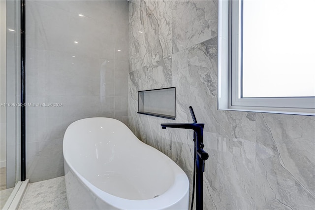 bathroom featuring a tub to relax in and tile walls