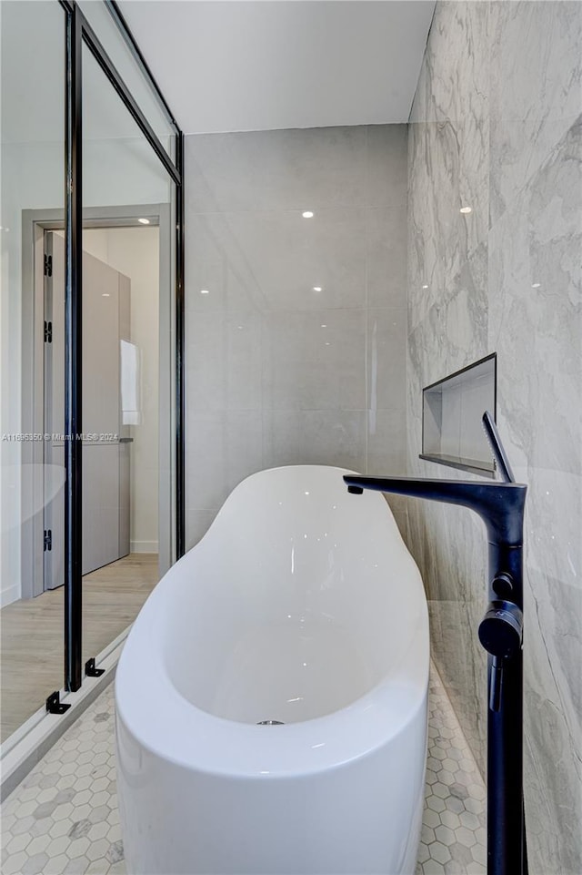 bathroom with tile patterned floors, tile walls, and a bathing tub