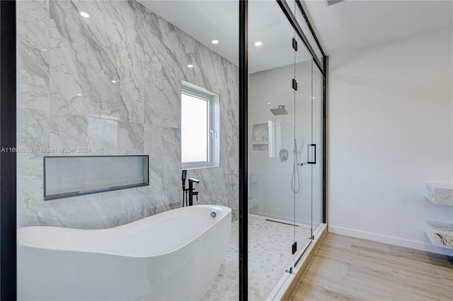 bathroom featuring wood-type flooring and shower with separate bathtub