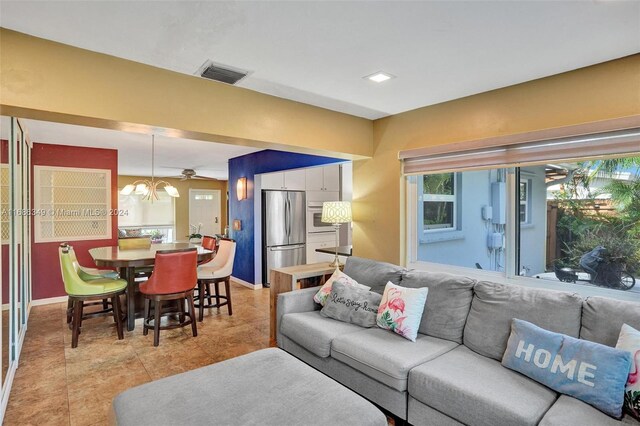 living room featuring light tile patterned flooring and ceiling fan with notable chandelier