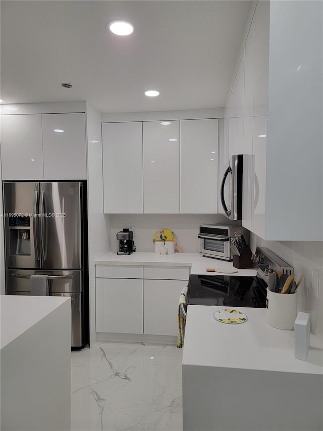 kitchen featuring light countertops, appliances with stainless steel finishes, white cabinetry, modern cabinets, and marble finish floor