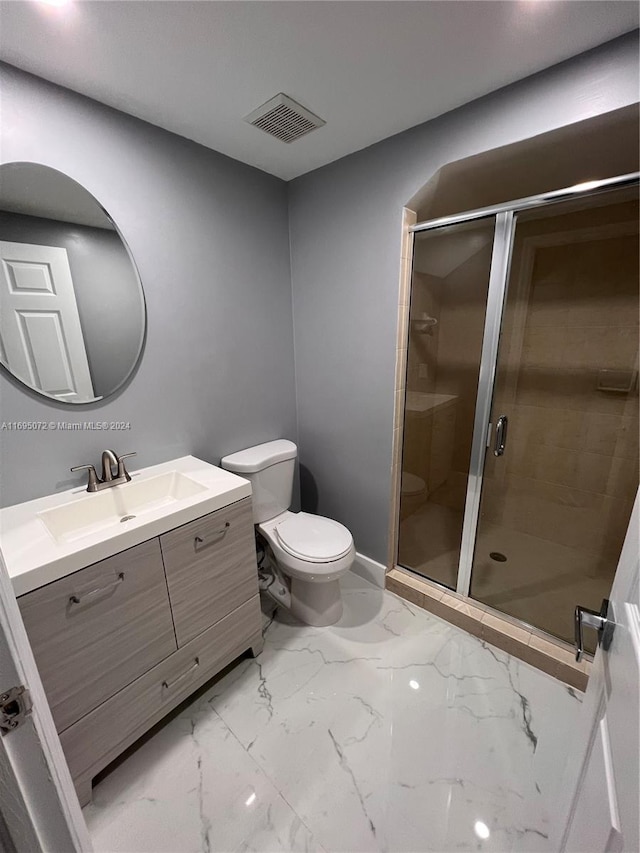 bathroom featuring vanity, toilet, and a shower with shower door