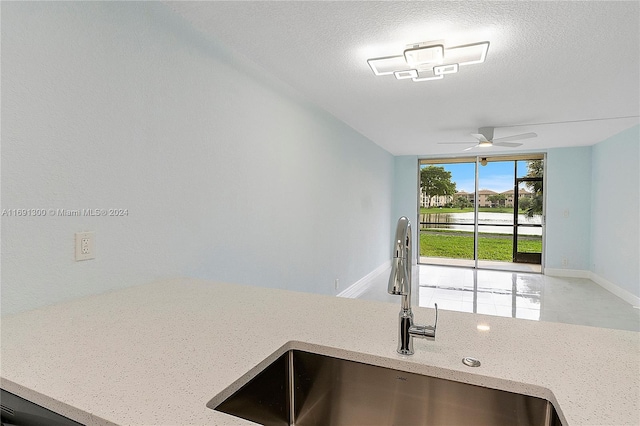 kitchen with ceiling fan, sink, and a textured ceiling