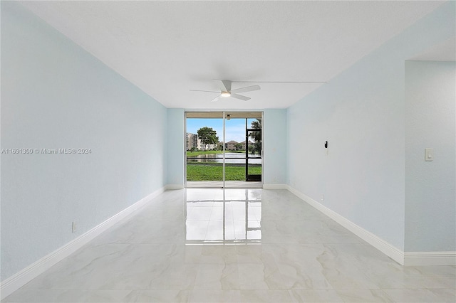 empty room featuring ceiling fan and expansive windows