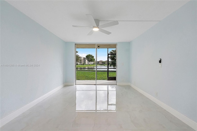 spare room featuring ceiling fan and a wall of windows