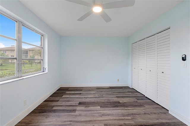 unfurnished bedroom with multiple windows, ceiling fan, a closet, and dark wood-type flooring