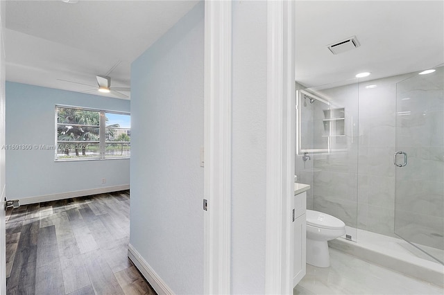 bathroom with hardwood / wood-style floors, vanity, ceiling fan, toilet, and a shower with shower door