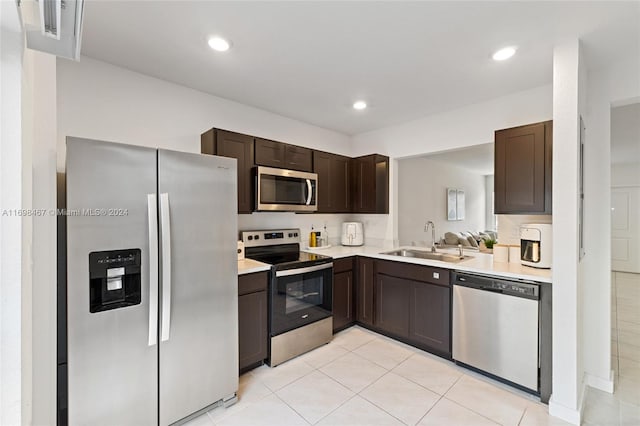 kitchen featuring sink, light tile patterned floors, dark brown cabinets, and appliances with stainless steel finishes