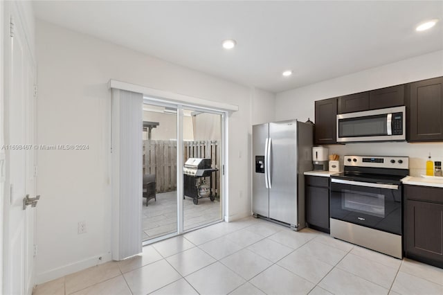 kitchen with dark brown cabinetry, light tile patterned flooring, and appliances with stainless steel finishes