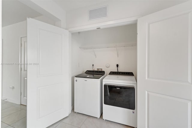 clothes washing area featuring washing machine and clothes dryer and light tile patterned floors