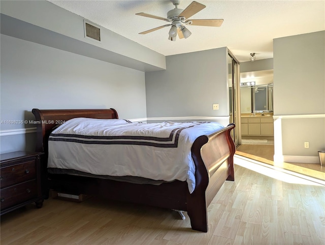 bedroom featuring ensuite bathroom, light hardwood / wood-style floors, a textured ceiling, and ceiling fan