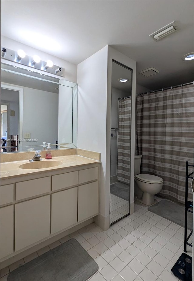 bathroom with tile patterned flooring, vanity, toilet, and walk in shower