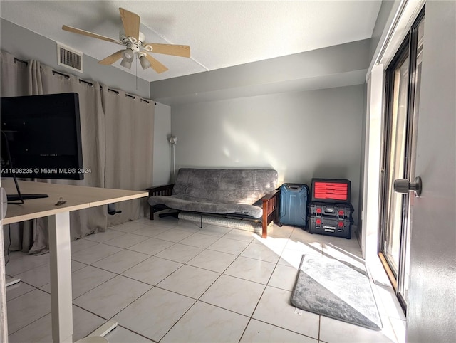 sitting room with ceiling fan, light tile patterned floors, and a textured ceiling